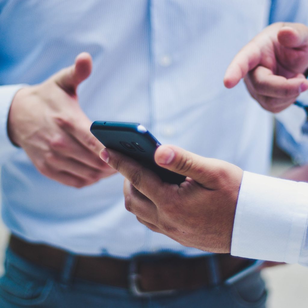 Homme qui montre son télephone à une autre personne